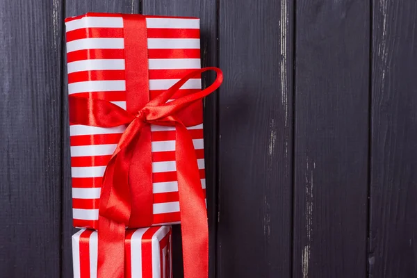 Diapositiva de regalos en una envoltura roja y blanca contra una cerca de madera negro . —  Fotos de Stock