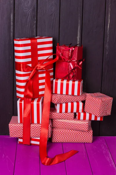 Diapositiva de regalos en una envoltura roja y blanca contra una cerca de madera negro . —  Fotos de Stock