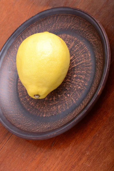 Lemons in a brown bowl on a wooden background — Stock Photo, Image
