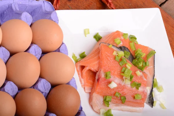 Fresh salmon fillet close up on white plate. red pepper, eggs and lemon — Stock Photo, Image