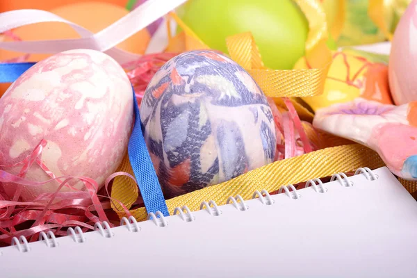 Handcrafted easter eggs close up, white notepad, ribbons and decoration — Stock Photo, Image