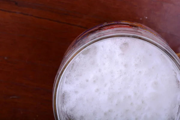 Vaso de espuma de cerveza sobre mesa de madera —  Fotos de Stock