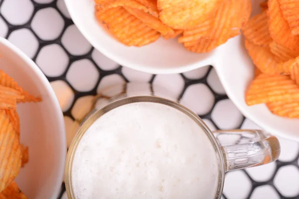 Vaso de cerveza ligera y papas fritas sobre un fondo abstracto. vista superior — Foto de Stock