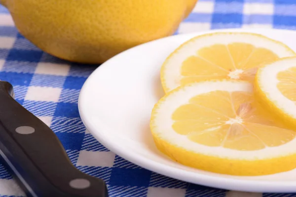 Halved lemon and a knife on a white plate — Stock Photo, Image