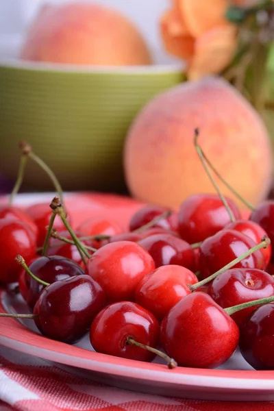 Närbild av färska söta körsbär i skål på bordet. Aprikos och apelsin — Stockfoto
