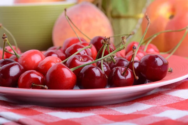 Närbild av sötkörsbär i skål på bordet. Aprikos och apelsin — Stockfoto