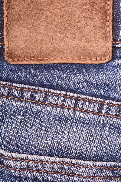 Läder etikett på denim jeans bakgrund, närbild. Brunt läder tag, dubbla sömmar, bandet på Mörk blå denim jeans — Stockfoto