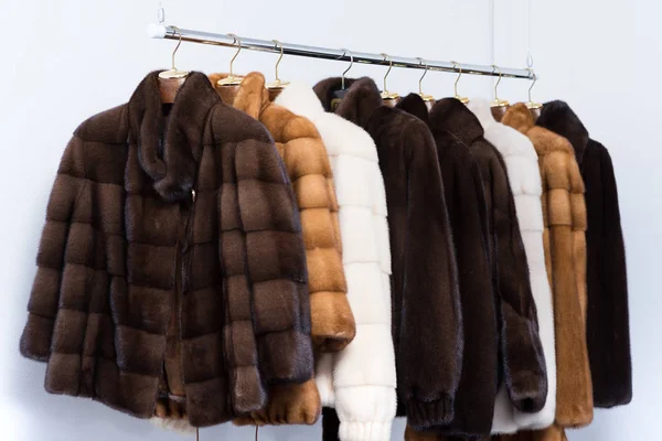 Меховые пальто на вешалках в салоне — стоковое фото