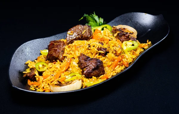 Un fel de mâncare cu orez și carne pe un fundal negru — Fotografie, imagine de stoc