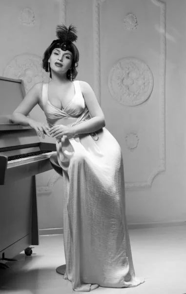Kobieta z pięknymi piersiami przy fortepianie — Zdjęcie stockowe