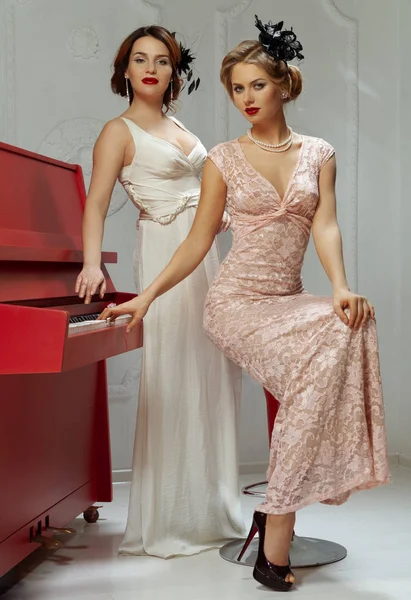两个女人穿着旧衣服站在钢琴旁边 — 图库照片