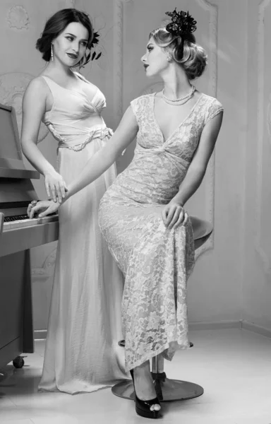 两个穿着复古服装的女人站在钢琴旁边 — 图库照片