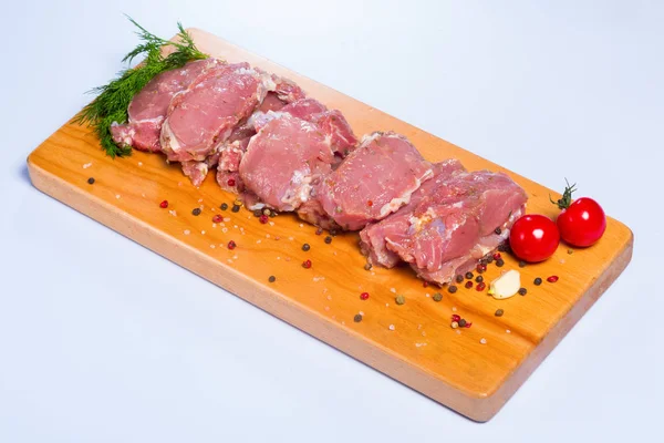 Raw beef meat and vegetables on a wooden board — Stock Photo, Image