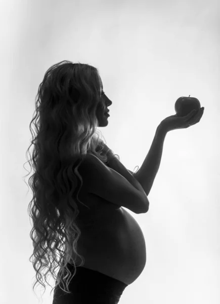 Silhouette of a pregnant girl with an apple — Stockfoto