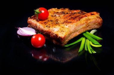 Siyah arka planda pirzola, sebze ve otlu et.