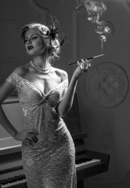 Stüdyoda piyanonun yanında sigara içen bir kız..