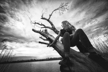 Kız ve gölün kenarında ölü bir ağaç, siyah ve beyaz.