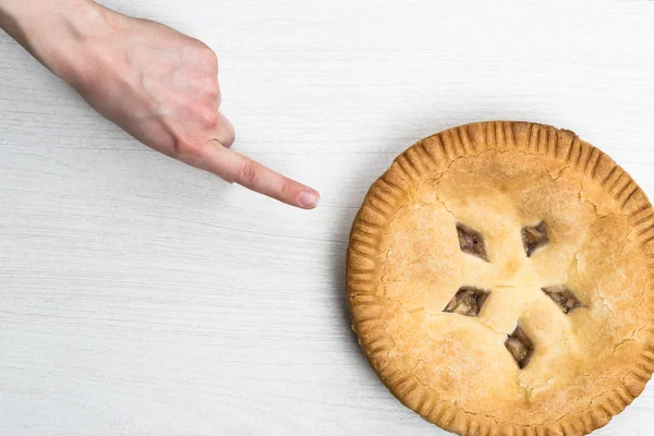 Apple pie cake lying on wooden white background with spoon in wo