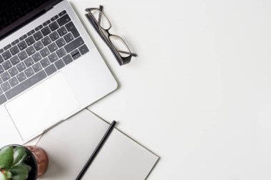 Üstten Görünüm office çalışma alanı'nın. Kopya alanı ile beyaz Masası. Düz yatıyordu manzara laptop, gözlük, kalem, defter ve yeşil çiçek tablo. Yaratıcı tasarımcı kavramı.