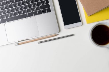 Üstten Görünüm office çalışma alanı'nın. Kopya alanı ile beyaz Masası. Düz yatıyordu görünümü ile dizüstü bilgisayar, kalem, telefon, kalem, defter ve sade kahve masada. Yaratıcı tasarımcı kavramı.
