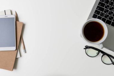 Üstten Görünüm office çalışma alanı'nın. Kopya alanı ile beyaz Masası. Düz yatıyordu görünümü ile dizüstü bilgisayar, telefon, dizüstü bilgisayarlar, gözlük ve kahve masada. Yaratıcı tasarımcı kavramı.