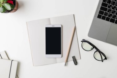 Üstten Görünüm office çalışma alanı'nın. Kopya alanı ile beyaz Masası. Düz yatıyordu görünümü ile dizüstü bilgisayar, telefon, çiçek, gözlük ve kalem masada. Yaratıcı tasarımcı kavramı.