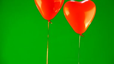 yeşil bir arka plan üzerinde kalp şeklinde iki kırmızı top