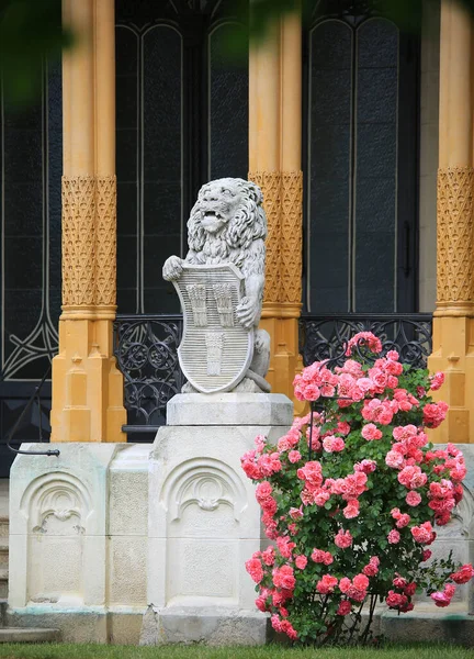 带有狮子雕塑和粉色玫瑰花丛的建筑 — 图库照片