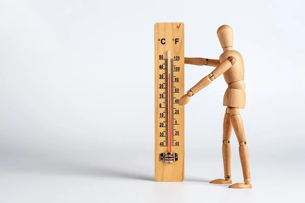 Hot summer weather, a wooden man measures the air temperature: celsius and fahrenheit scale thermometer for measuring air temperature. Objects isolated on white background, space for text.