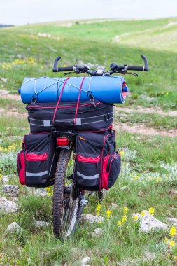 Sırt çantalı yalnız bir dağ bisikleti yamaçta duruyor. Bisiklet yolculuğu kavramı. Bisiklet turizmi için ekipman.