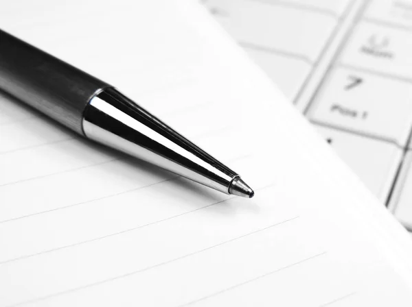 Penna och papper på en vit laptop tangentbord — Stockfoto