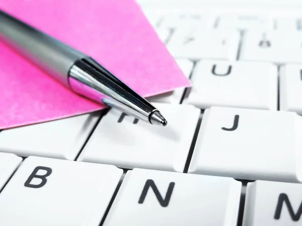 Penna och papper på en dator tangentbordet — Stockfoto