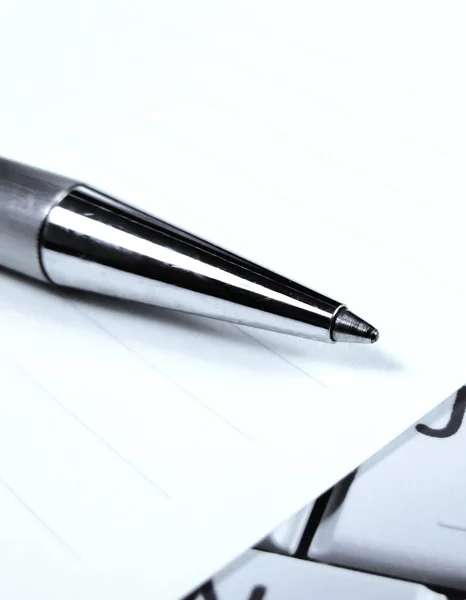 Penna och papper på en vit laptop tangentbord — Stockfoto