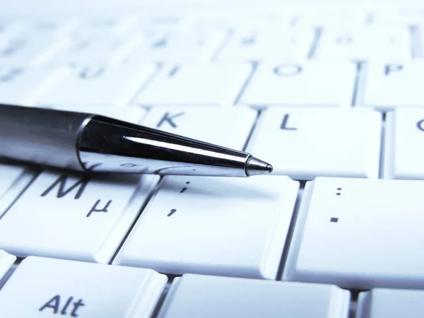 Ручка і папір на білій клавіатурі ноутбука — стокове фото