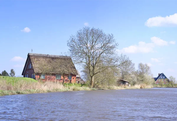 Reetdachhaus an einem Flussufer — Stockfoto