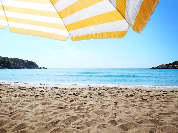 Beach scene with striped sunshade — Stock Photo, Image