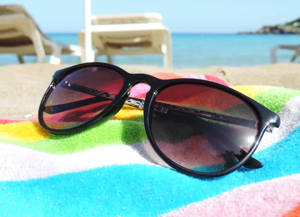 Napszemüveg egy tarka törülközőt a strandon — Stock Fotó