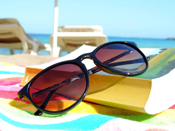 Napszemüveg és a könyv a strandon — Stock Fotó
