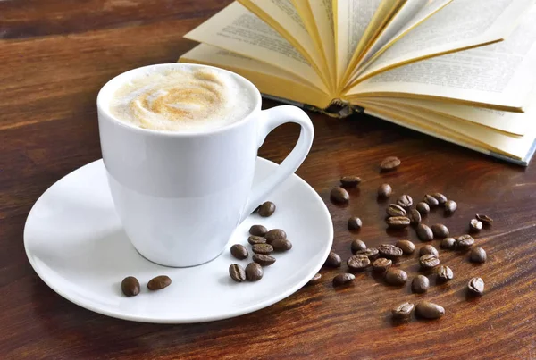 Frühstücksszene mit Kaffeetasse, offenem Buch und Kaffeebohnen — Stockfoto