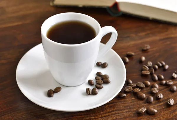 Breakfast scene with coffee cup, open book and coffee beans — Stock Photo, Image