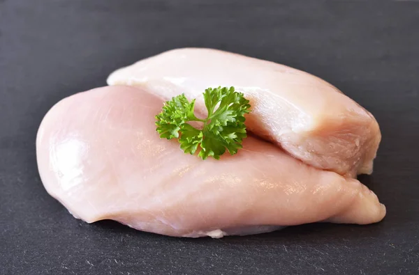 Pechuga de pollo cruda en un plato de pizarra, con perejil fresco — Foto de Stock