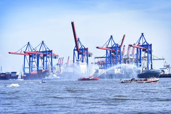 Harbor cranes and firefighter ship with water fountains