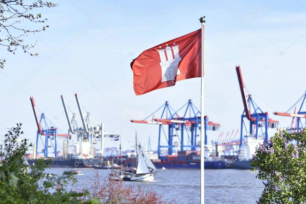 View to Hamburg harbor with harbor cranes and Hamburg flag in focus