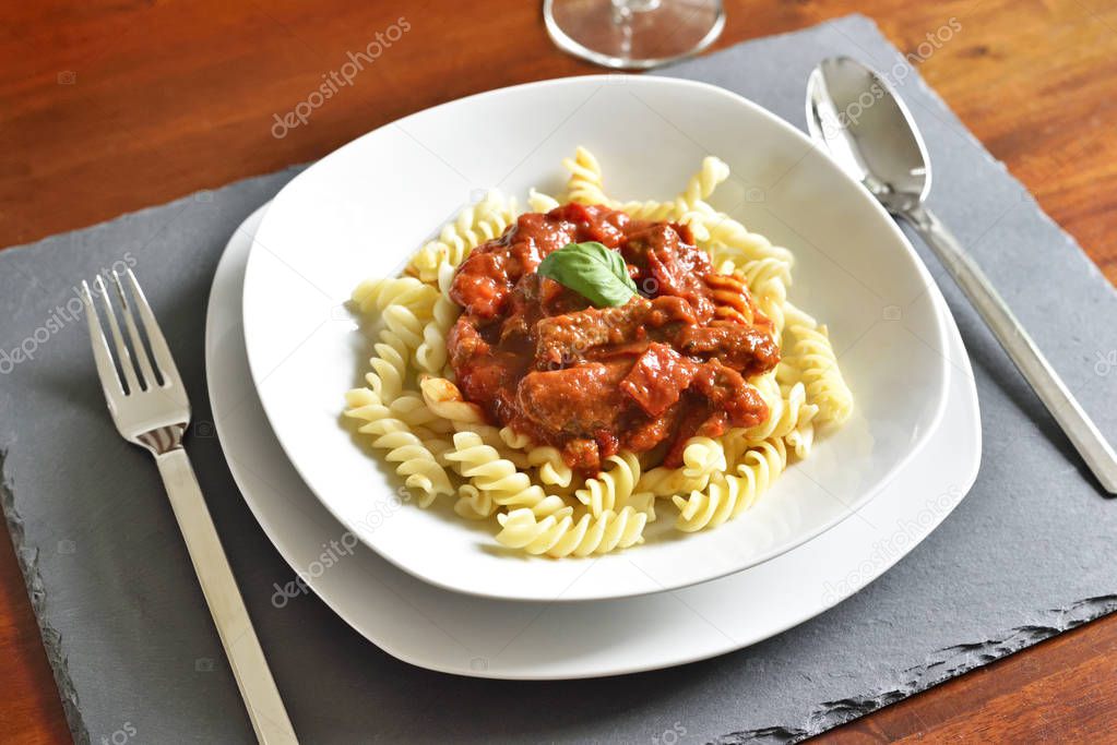 Delicious goulash dish on a white plate with basil leaf