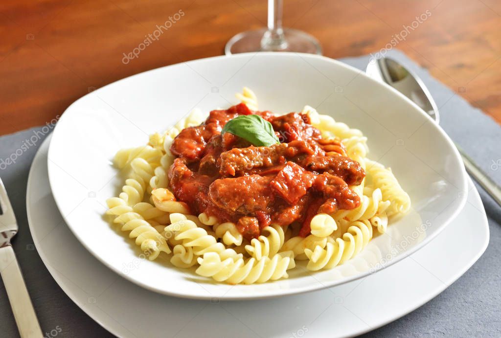Delicious goulash dish on a white plate with basil leaf