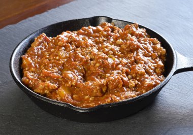 Bolognese sosu bir pişirme pan veya demir tavada. İtalyan mutfağı arka plan ile makarna sosu ve kayrak plaka.