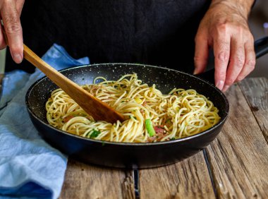 Bir şef makarna pişirmek için sebze ve pastırma hazırlıyor.
