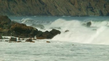 Kayaların üzerinden inişli çıkışlı dalgalar