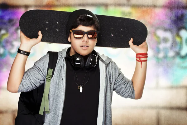 Stylish teen boy with skateboard — Stock fotografie