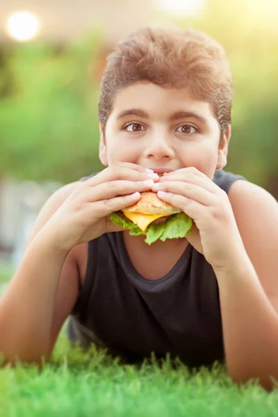 Adolescente chico comer hamburguesa — Foto de Stock